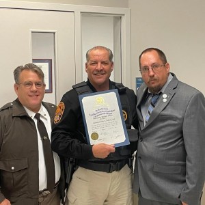 Sheriff Mark Butler and Worshipful Master Will Bryan pose with Lieutenant Robert Seal holding his Community Builder Award on October 18, 2022.