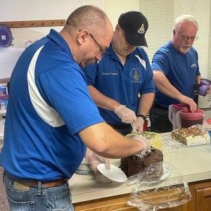 Will and Charles cut slices of cake to be served in the Thermal Shelter on January 5, 2023 at Front Royal Presbyterian Church.