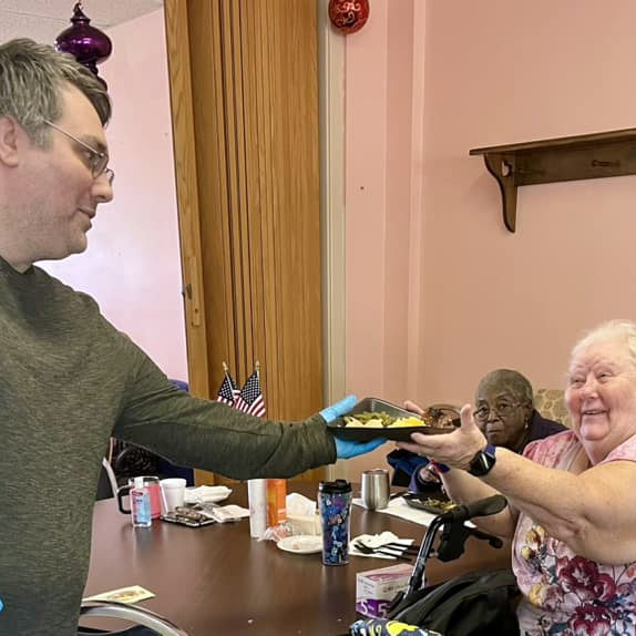 Brother Lewis Moten of the Masons serves a warm meal to a senior at the Warren County Senior Center on August 11, 2023