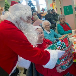 Santa Clause (Played as Terry Fritts) hands a basket full of Christmas Gifts to a Senior Citizen at the Warren County Senior Center on December 20, 2023