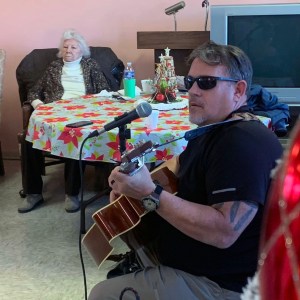 Sheriff Mark Butler plays an acoustic guitar while wearing sunglasses at the Warren County Senior Center on December 20, 2023.jpg