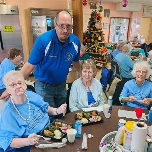 Will Bryan poses with a table of seniors enjoying the Thanksgiving meal he prepared on November 17, 2022