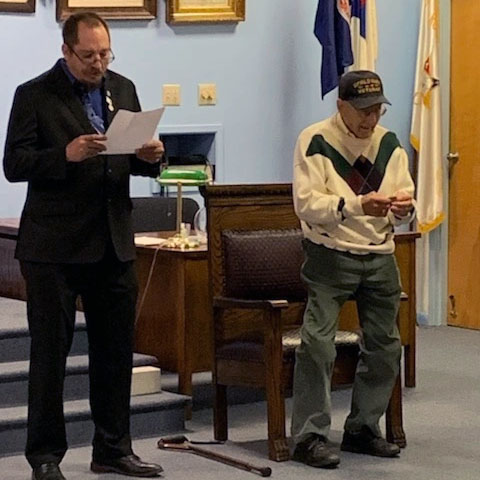 Will Bryan reads a list of Bill Woods achievements while Bill looks at his award on December 15, 2021