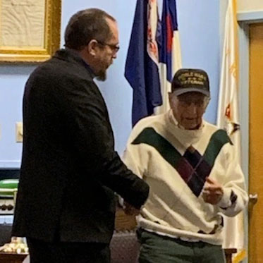 Will Bryan shakes Bill Woods hand after awarding him with a merit award on December 15, 2021