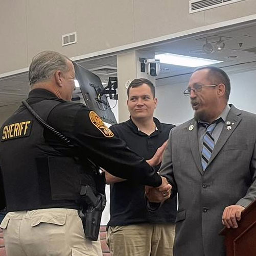 Will Bryan shakes hands with Lt. Robert Robbie Anthony Seal after receiving the Community Builder Award on October 18, 2022